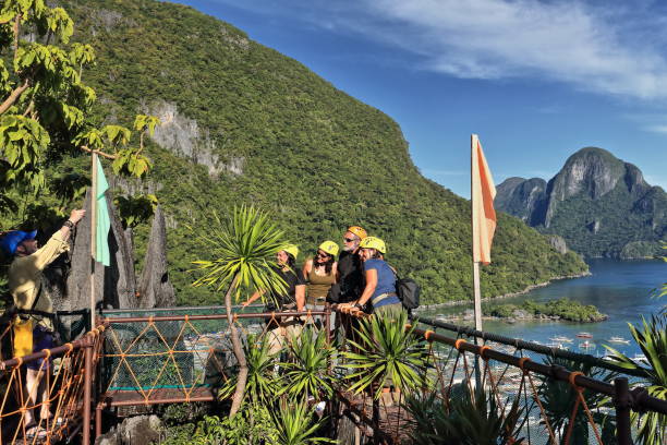 El Nido, Palawan, Philippines-October 23, 2016: Visitors climb to Taraw cliff overlooking the town to enjoy the view of the port-tour boats anchored while waiting to go out on island hopping tours.