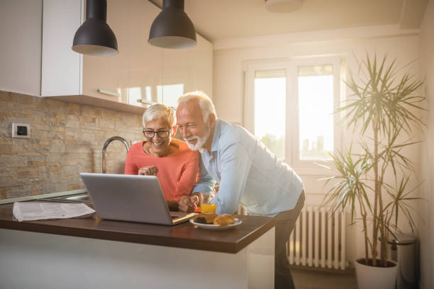 We love to video chat with our family Senior couple staying in touch with their family using their laptop at home candid bonding connection togetherness stock pictures, royalty-free photos & images