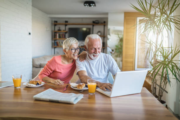 Senior couple shopping online Senior couple shopping online from their home financial wellbeing stock pictures, royalty-free photos & images