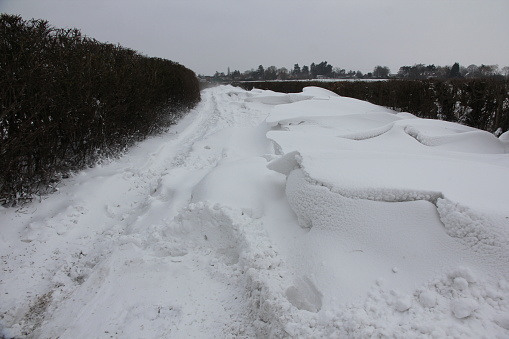 Deep snowdrifts and vehicles tracks along isolated rural lane