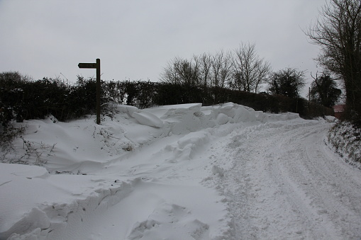 Vehicle tracks on snow covered road with large snowdrifts in verges