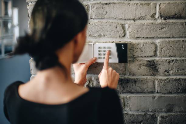 Young woman entering security pin on home alarm keypad. stock photo