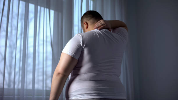 男性の肥満、太りすぎによる腰痛問題の首の筋肉をストレッチ - human spine backache pain back ストックフォトと画像