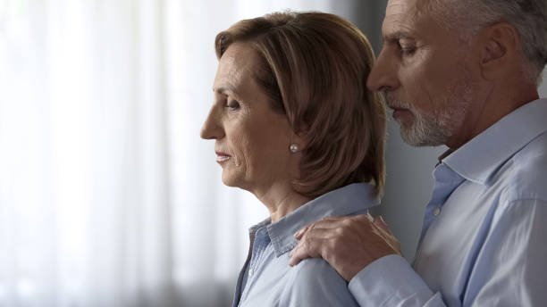 istock Depressed aging lady standing by window, spouse taking her by shoulders, support 1088258372