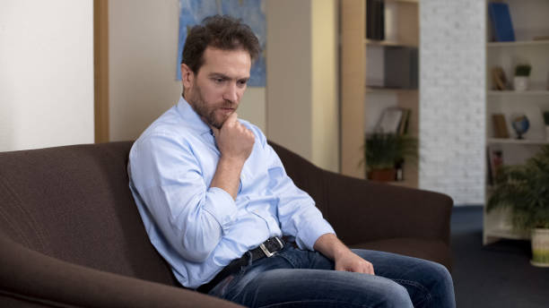 istock Thoughtful mid-aged male on couch thinking about money loss, negative emotions 1088258462