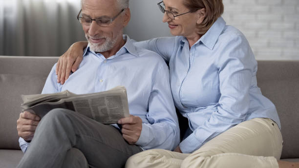 istock Aged husband reading newspaper, wife hugging him with love, harmonious couple 1088258618
