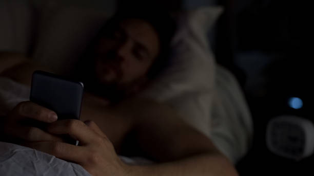 istock Sleepless male lying in bed, chatting on smartphone, gadget addiction, insomnia 1088258632