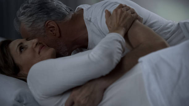 aged male kissing woman neck, couple hugging and caressing in bed, attraction - passion sexual activity sexual issues sex imagens e fotografias de stock