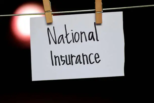 National Insurance handwriting on paper. Hanged with a clothes clips, medical and education concept. light blur background