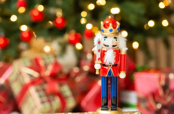 Christmas nutcracker figurine. Christmas tree and presents, bokeh background.