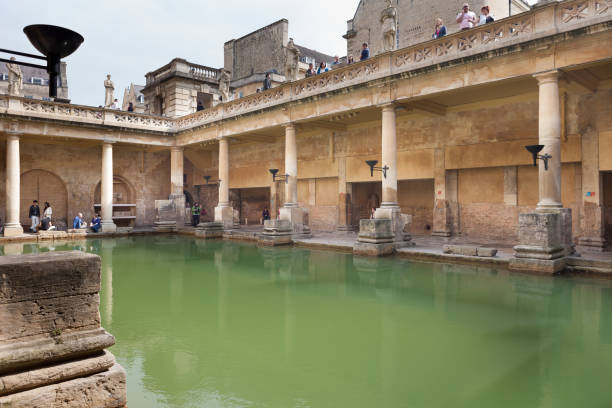 Tourists in Bath, Somerset, UK. Bath, United Kingdom - April 18, 2011: Tourists walking around the main pool at the Roman Baths in Bath, England. ancient rome stock pictures, royalty-free photos & images