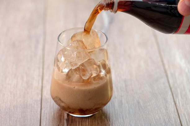 istock Soda (cola) being poured into plain glass with ice 1088349538