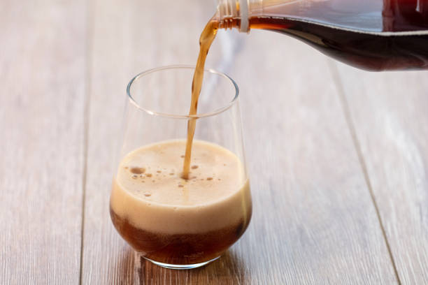 istock Soda (cola) being poured into plain glass with ice 1088353422