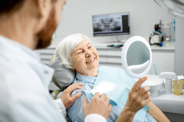 Elderly woman enjoying her smile in the dental office Happy elderly woman enjoying her beautiful toothy smile looking to the mirror in the dental office dentures stock pictures, royalty-free photos & images