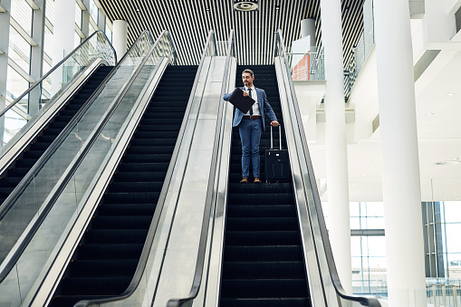 Shot of a mature businessman checking the time while traveling on an escalator in an airport
