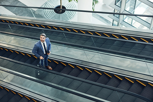 Shot of a mature businessman traveling on an escalator in an airport