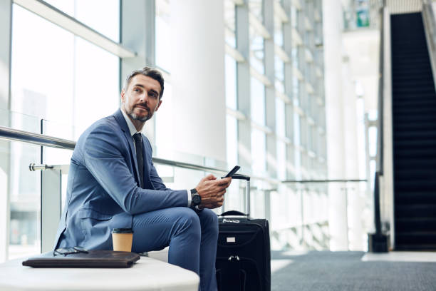 On call for success Shot of a mature businessman using a mobile phone in an airport airport departure area stock pictures, royalty-free photos & images