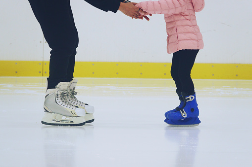 padre enseñando a hija a patinar en la pista de patinaje sobre hielo photo