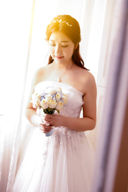 istock Bride holding flowers, by the window 1088415726