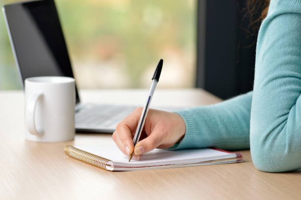 writing in my note book Female hand writing notes in a notebook on a desk at office ballpoint pen photos stock pictures, royalty-free photos & images