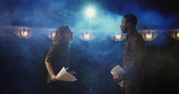 Actors rehearsing a scene in a theater Medium shot of an actor and actress rehearsing a scene in the theater while holding their scripts stage actress stock pictures, royalty-free photos & images