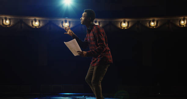 Actor performing a monologue in a theater Medium close-up shot of an actor performing a monologue in a theater while holding his script actor stock pictures, royalty-free photos & images