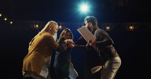 Actors celebrating on stage Medium shot of actors and actresses throwing scripts away and hugging while celebrating on stage in a theater actor stock pictures, royalty-free photos & images