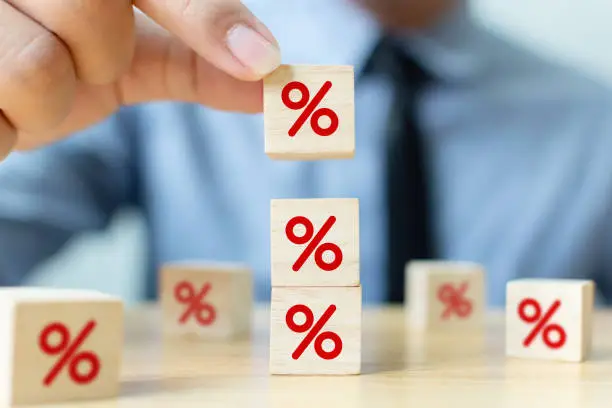 Photo of Interest rate financial and mortgage rates concept. Hand putting wood cube block increasing on top with icon percentage symbol upward direction