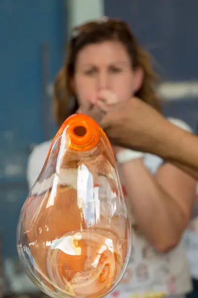This woman is trying the art of glass blowing in a glass blowing factory in Cabo San Lucas, Mexico.  This factory is a common spot for tourist visits and the professional glass blowers like to give tourists a try at blowing up a glass bubble.  This bubble was quickly broken and discarded after the fun was over.