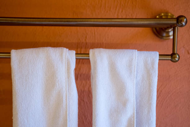 asciugamano appeso a un lungo portaasciugamani in acciaio inossidabile su sfondo a parete arancione. - towel hanging bathroom railing foto e immagini stock