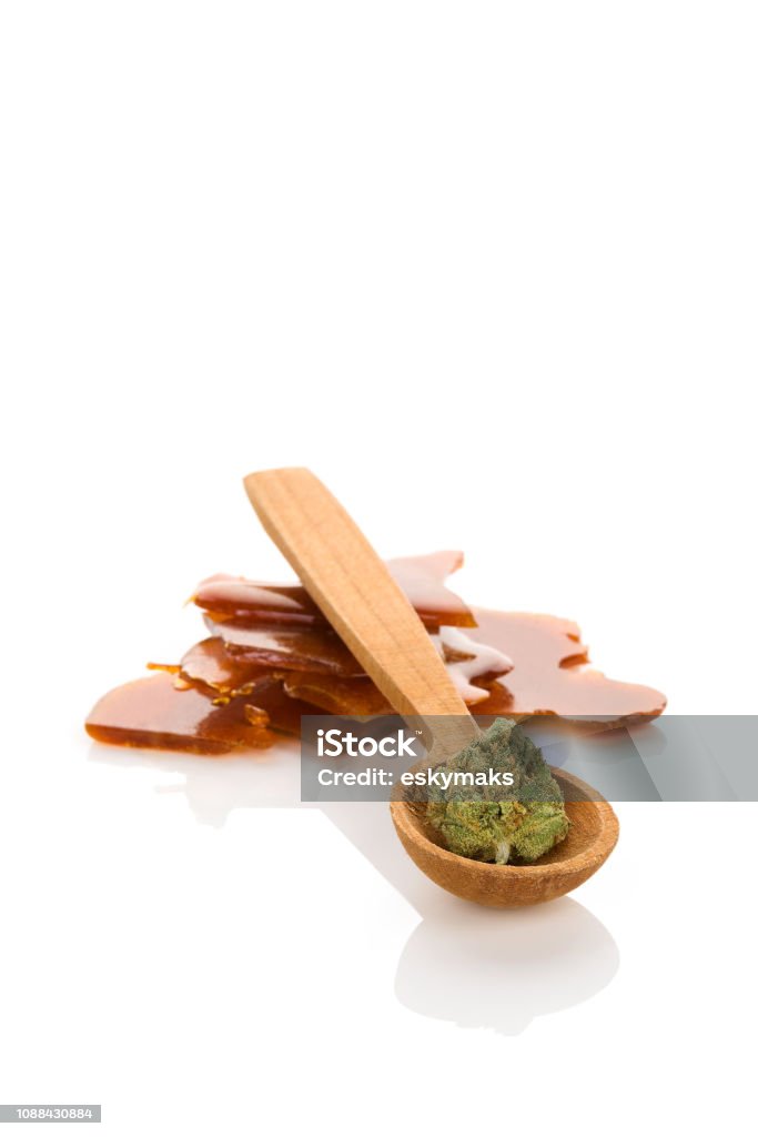 Cannabis bud and concentrates. Cannabis bud on wooden spoon and shatter concentrate isolated on white background. Cannabis - Narcotic Stock Photo