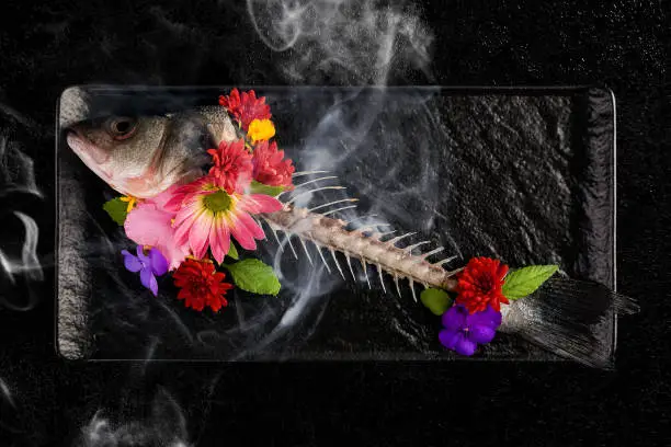 Photo of Skelet of fish with flowers and smoke.