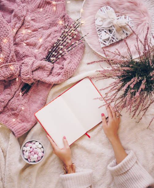 Female hands holding an open blank notebook. Coziness and comfort concept flat lay
