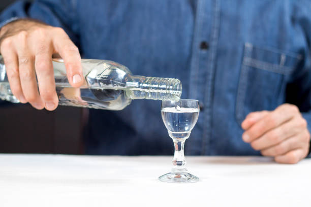 male hand pours vodka from the bottle into the glass. - bad habit imagens e fotografias de stock