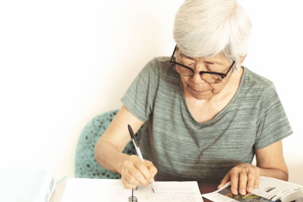 istock Senior woman taking notes while reading a book at home. 1088453286