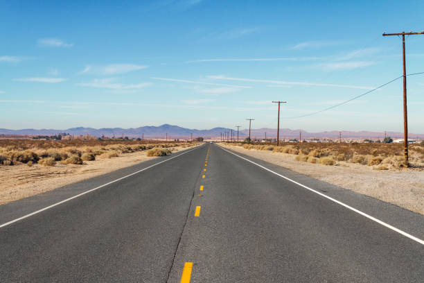 バック グラウンドでの山の範囲と長い平らな砂漠の道 - desert road road highway california ストックフォトと画像