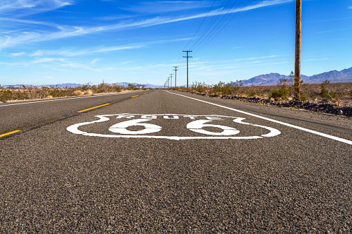 Ground level road view of Route 66 with logo in the Mojave Desert.