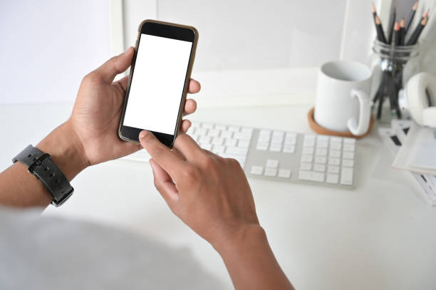 istock Mockup smartphone on man hands empty display with office desk background. 1088462580