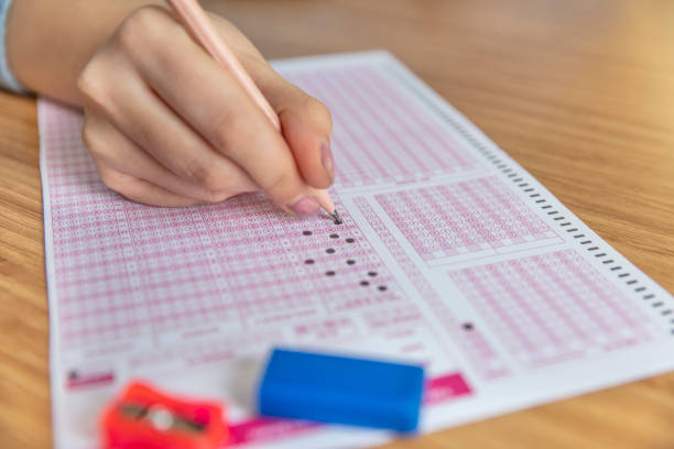 istock hand student testing in exercise and taking fill in exam carbon paper computer sheet with pencil at school test room, education concept 1088503296