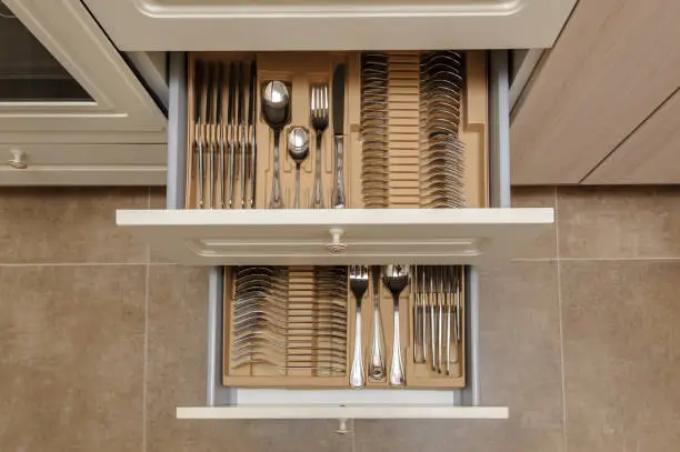 Opened kitchen drawer with silverware sets, view from above