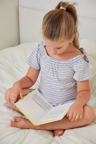 istock Little girl sitting on bed reading book 1088537972