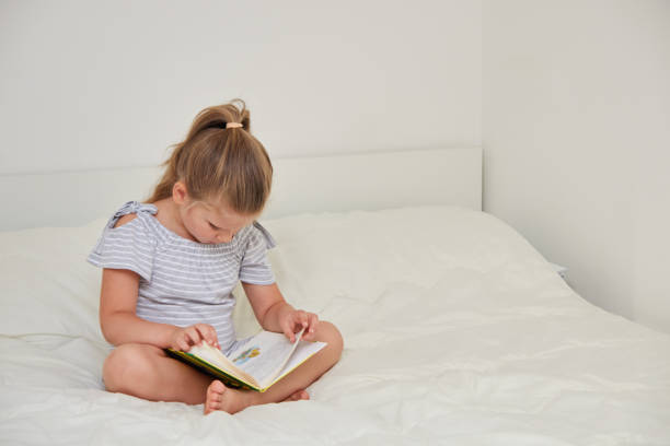 istock Little girl sitting on bed reading book 1088537978
