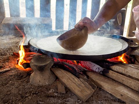 Baking a yuka-based bread on a plate made of fireclay. It is a traditional Siona food. Picture taken in one of Siona indigenous villages in Cuyabeno Wildlife Reserve, Ecuador.
