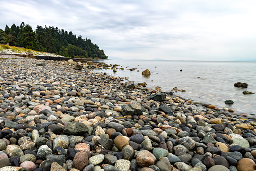 Long exposure of Wet rocks on shore with calm water with clouds in the distance