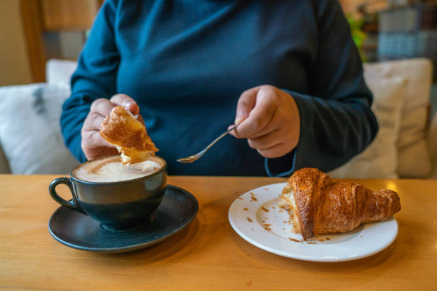 istock Woman eating croissant and drinking coffee 1088596854