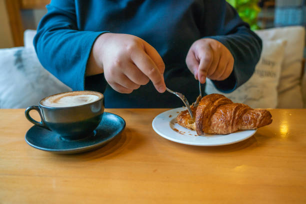 istock Woman hands eating croissant with fork and knife 1088596856