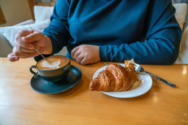 istock Young woman eating croissant while sitting in cafe, coffee break 1088596888