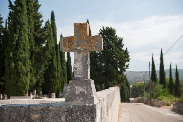 Old cross on a graveyard wall. Cross made out of stone. Religious symbol.