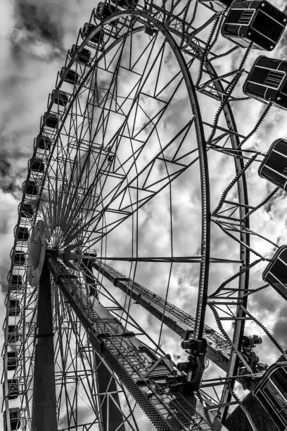 Ferris wheel taken at a funfair in Basel. Lots of Clouds in the sky and black and white photo.