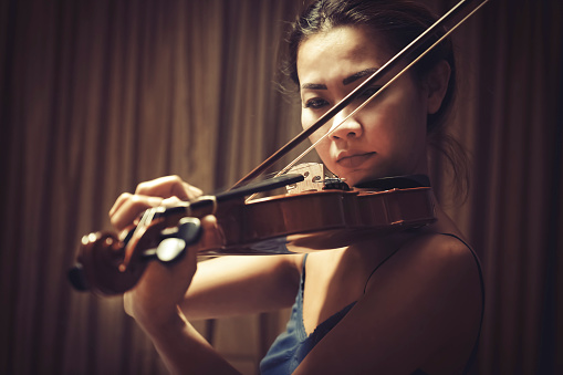 Female Asian violinist playing music on stage